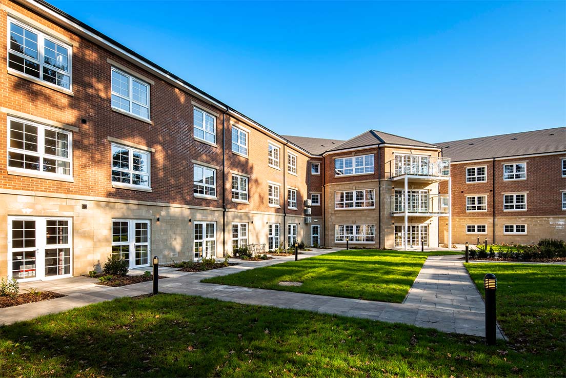 landscaped gardens with flat paths in front of large scottish care home