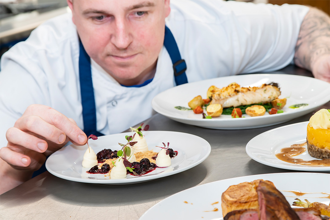 care home chef adding a garnish to a meal