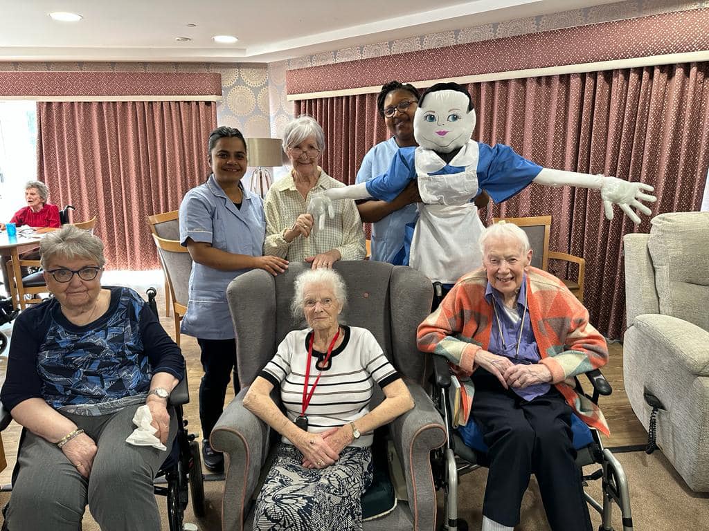 Residents & Staff with The Large Alice in Wonderland Doll