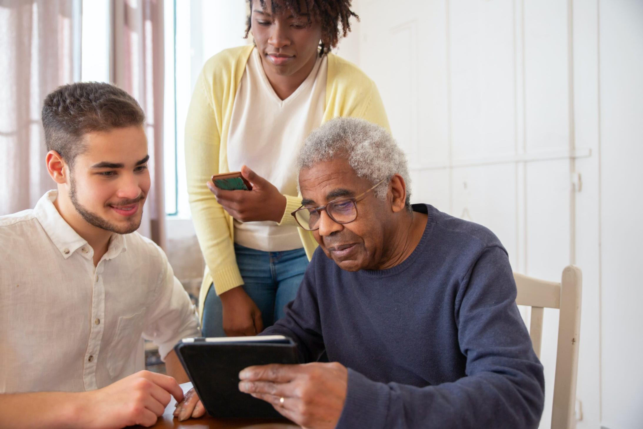 man helping elderly couple with tablet