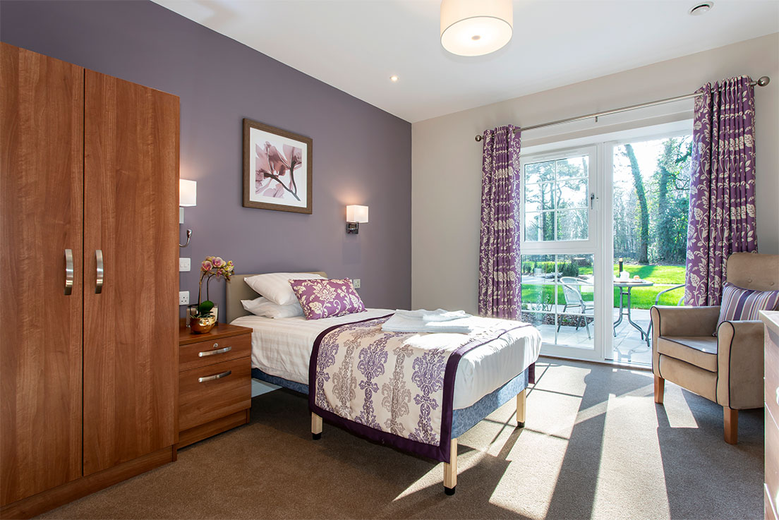 purple decorated bedroom with sun coming in through patio doors