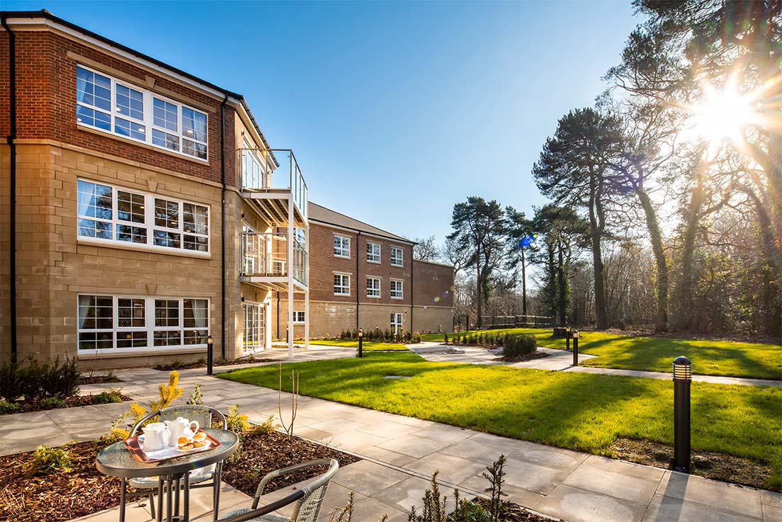 patio with garden furniture and sun shining through trees