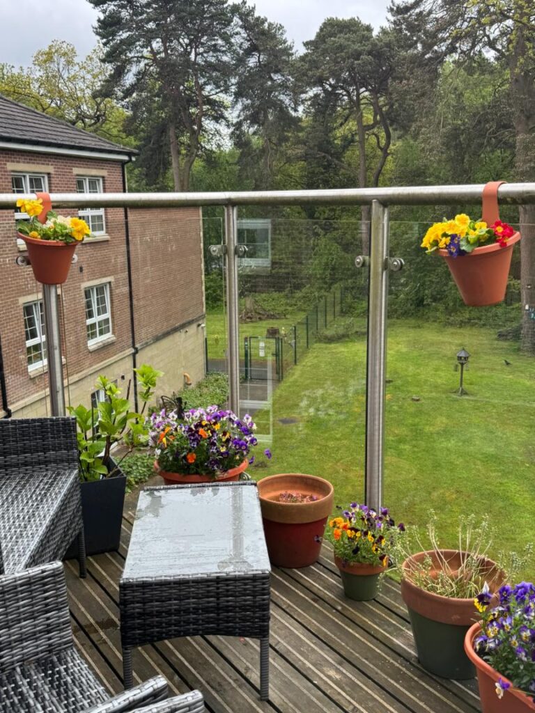 pots of colourful flowers on a glass-walled balcony