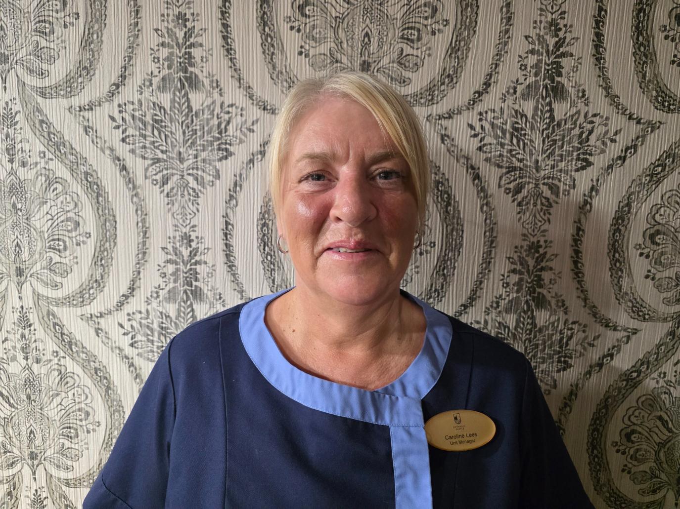 woman in front of patterned wallpaper in nurses uniform