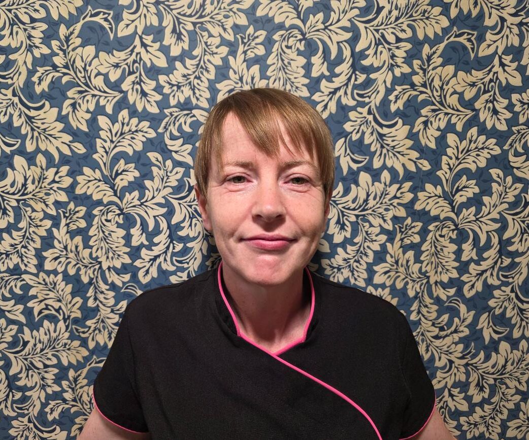 woman in front of patterned wallpaper in nurses uniform