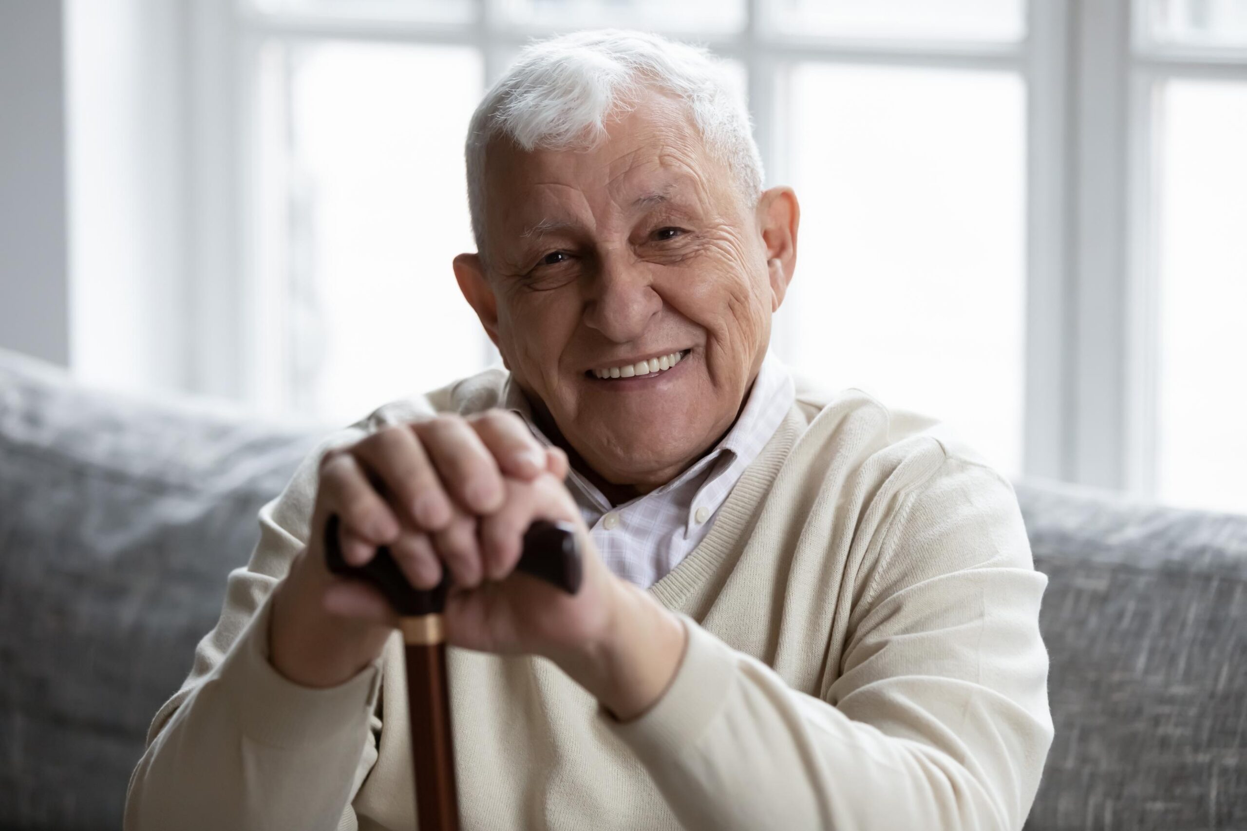 elderly man smiling holding a walking stick