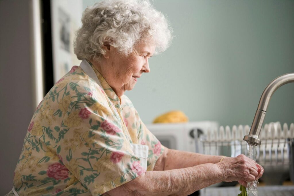 elderly woman washing her hands at home