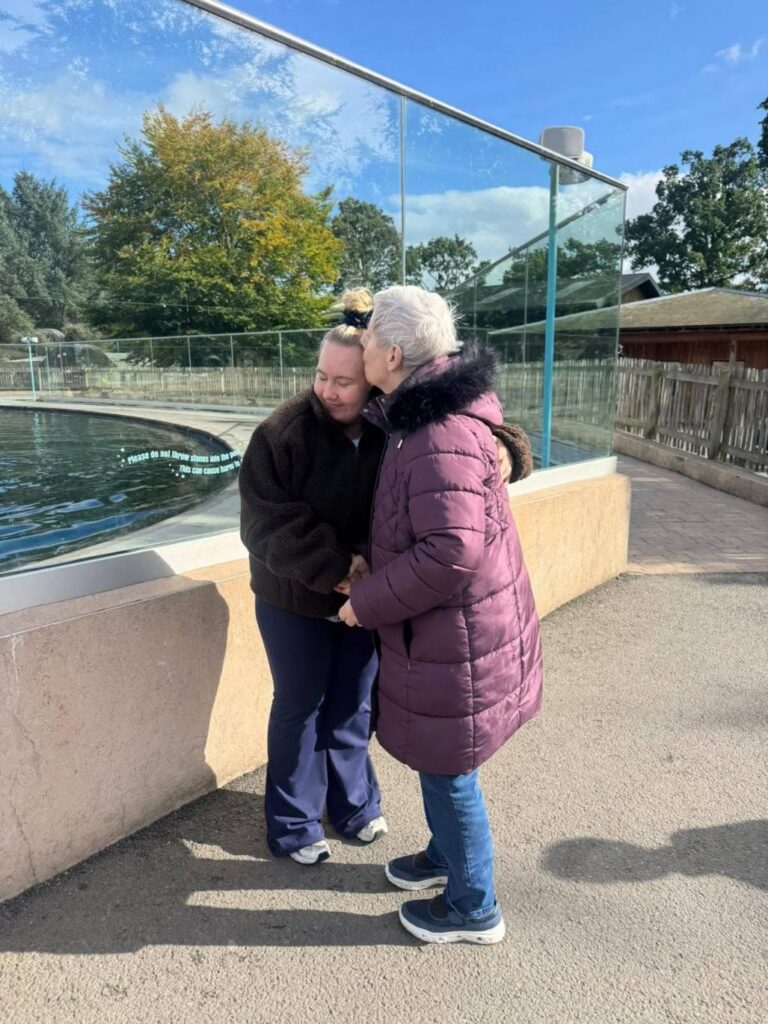 female care home resident kissing a care worker on the forehead